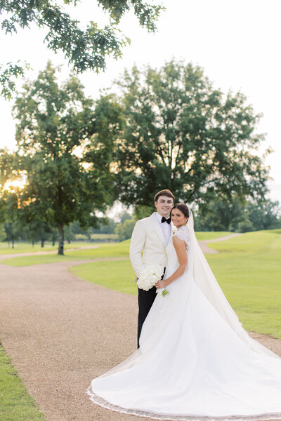 Bride wearing a veil and holding a bouquet of flowers on a summer day in Mississippi