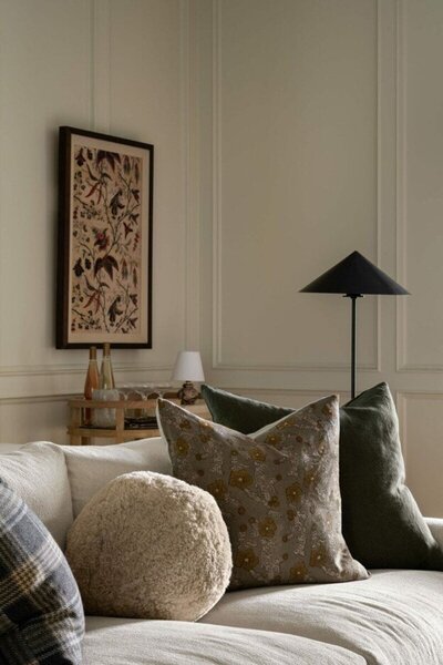 A well-furnished living room showcasing a sofa with decorative pillows and a lamp, creating a warm atmosphere.