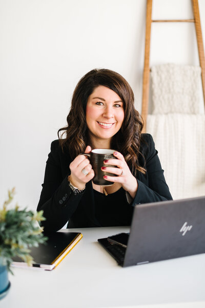A woman holds a coffee cup in her minimalistic office
