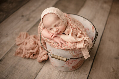 Newborn in girly bucket wrapped in pink blankets