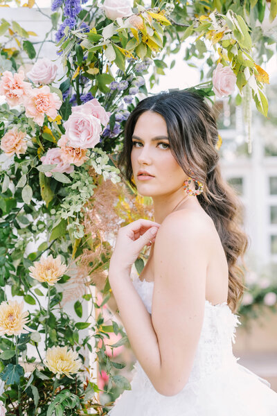 Stunning bride poses under lush floral installation on her wedding day