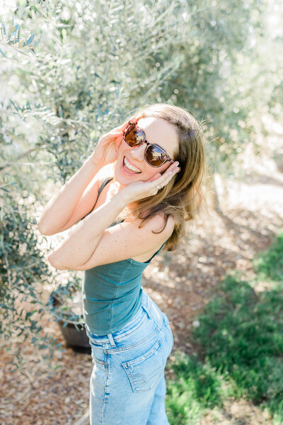 Where to get senior pictures taken near me? Picture of a girl smiling with sunglasses in an olive grove.