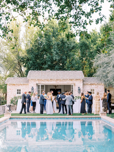 A stunning private estate wedding reception with guests mingling poolside. Captured in fine art luxury wedding photography for a timeless, elegant celebration.