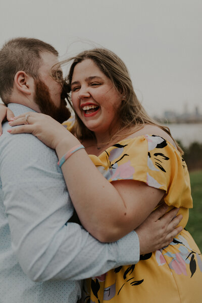Couple share a windswept hugafter a surprise proposal at Edgewater Park in Cleveland, Ohio