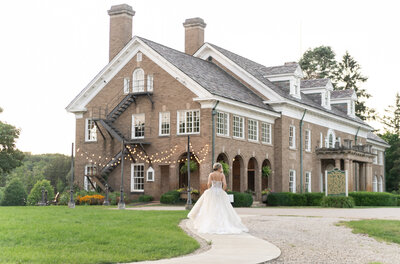 bride holding her dress as she walks toward the Felt Mansion in Holland