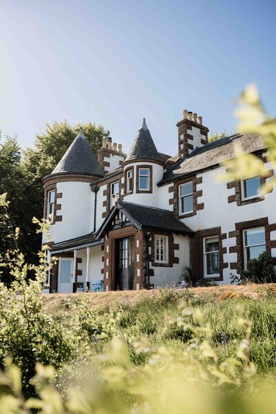 The front of Kinlcune House Wedding Venue is photographed underneath the blue summer sky.