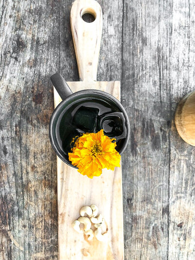 A top shot of a mug with dark liquid inside and an orange flower sticking out.