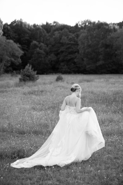 bride holding her wedding dress walking through the field at the Felt Mansion