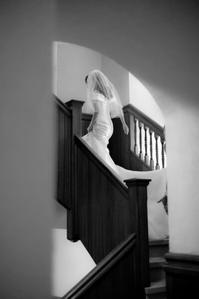 black and white photo of bride walking up a staircase