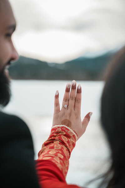 Engagement ring shown between blurred man and woman.