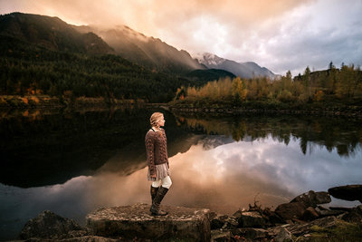 Young woman standing by the lake surrounded by nature