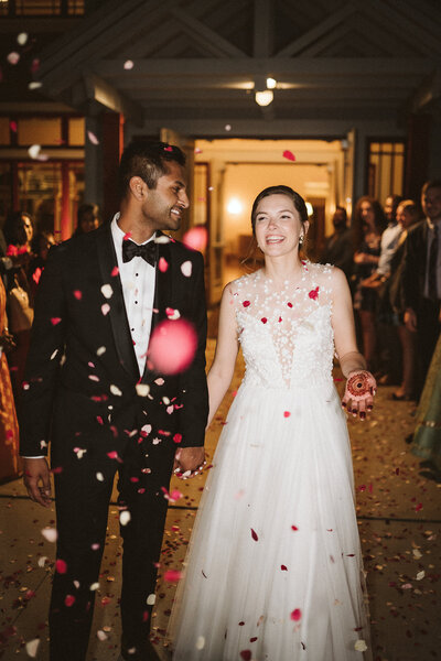 Bride and groom walking hand in hand for their send off as flower petals are thrown around them, taken by Asheville Wedding Photographer Simon Anthony Photography