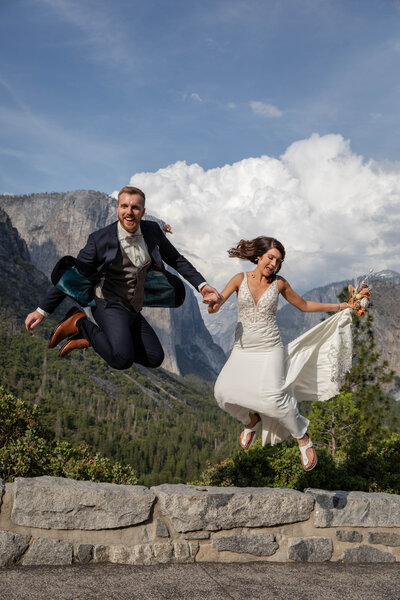 Bride and groom jump into the air off of a rock wall in Yosemite on their adventure elopement day.