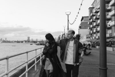 Couple walking on San Francisco Pier as man puts arm around woman