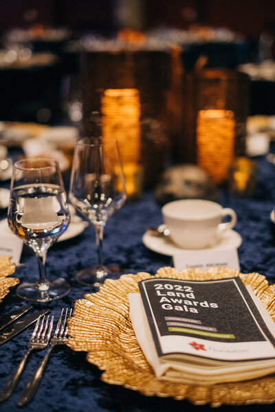 Elegant gala table set with glassware, plates, and event program.