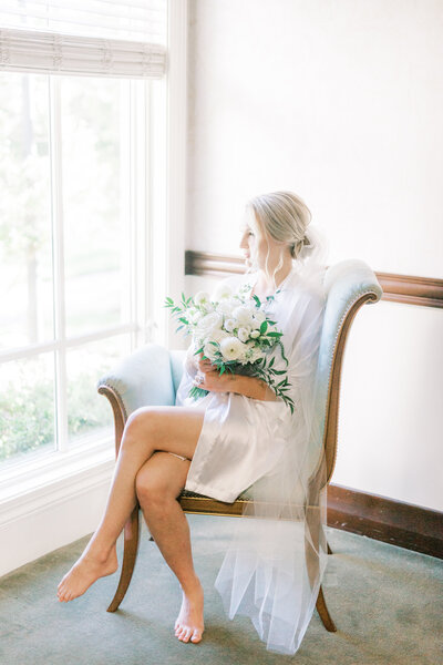 Bride holding bouquet while getting ready