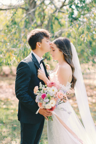 groom kissing brides head