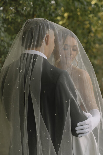 Intimate moment for bride and groom covered in bride's veil