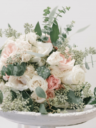 A wedding magazine surrounded by a Canon camera, red and pink cloth, flowers, leaves and a wedding ring