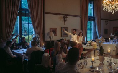 Bride and groom making a toast during their wedding reception, laughing and having a very joyful moment.