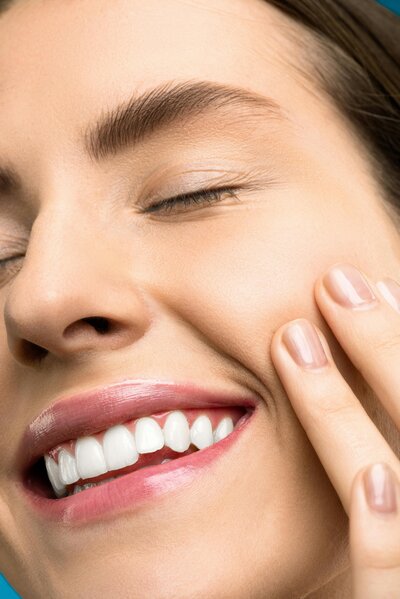A close up photo of a woman smiling after smile lines.
