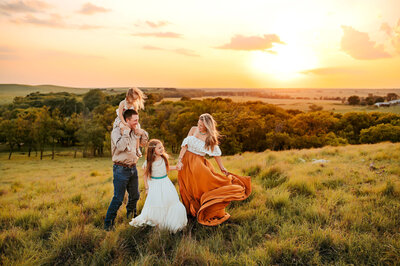 Mother swaying her long dress, holding her oldest daughters hand while smiling at her youngest child.