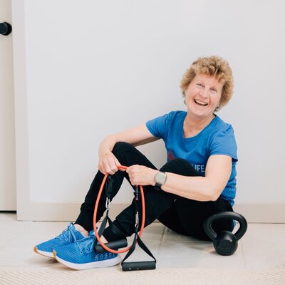 Coach Helen Ann demonstrating a weighted front lunch with dumb bells in hand