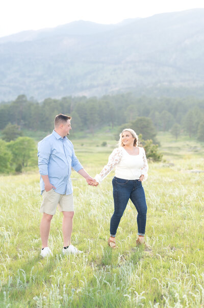 Couple walking together in meadow at Rocky Mountain National Park holding hands