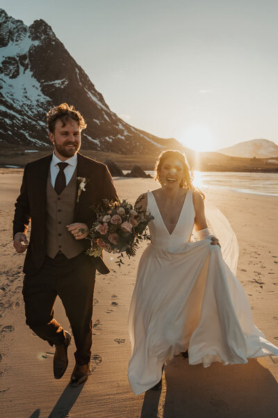 Wedding couple running on a beach at sunset in Lofoten