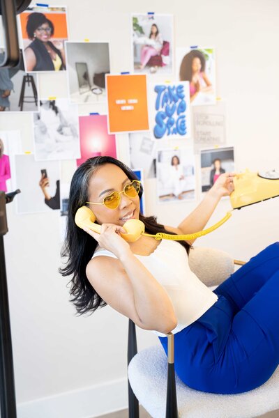 Creative brand photographer in her professional studio surrounded by branded images on the wall, capturing the essence of brand photography in a visually curated space