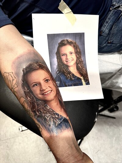 A beautifully detailed portrait tattoo of a daughter, capturing lifelike features and emotional depth with expert shading and realism.