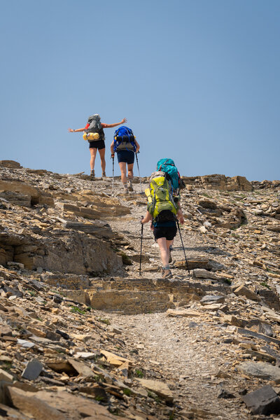 A group of backpackers crest the top of a trail in Glacier National Park in Montana
