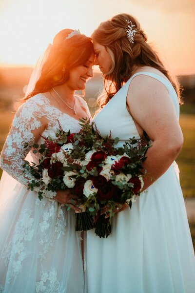 Lesbian brides touching foreheads at Bella Collina