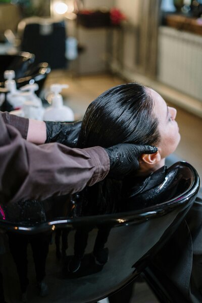 Client having scalp massaged in shampoo bowl 