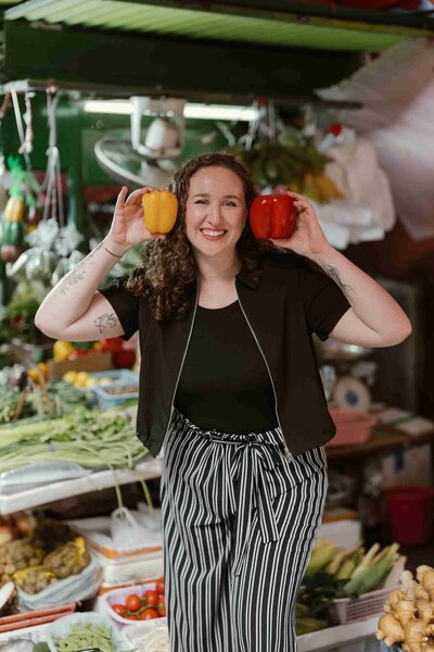 Christy Walowit holds peppers to her head in a playful pose.