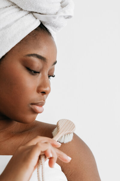 Close-up of woman dry brushing shoulder with a soft body brush for exfoliation