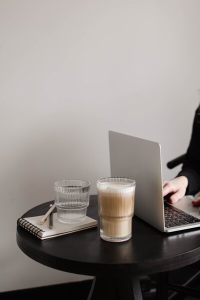 Notebook, glasses, and glassware beside a laptop – Brand Identity Express
