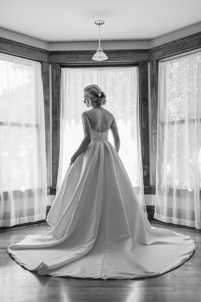 bride standing in wedding gown near windows