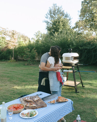 couple hugging while making pizza during at home engagement photos, captured by Elsie Goodman, an NYC engagement and couples photographer