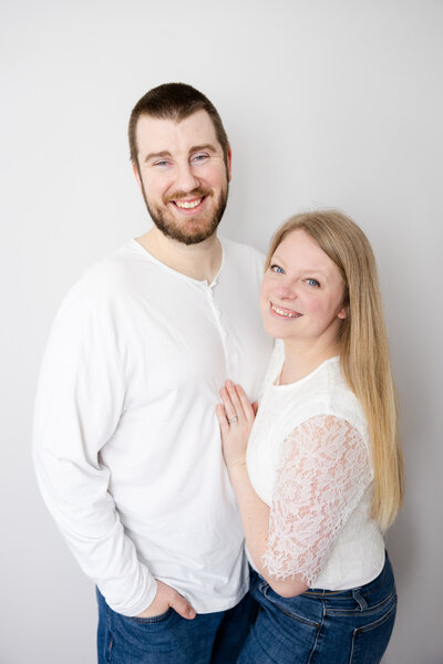Husband and wife wearing white shirts and jeans in their home in Beavercreek, Ohio smiling at the camera.