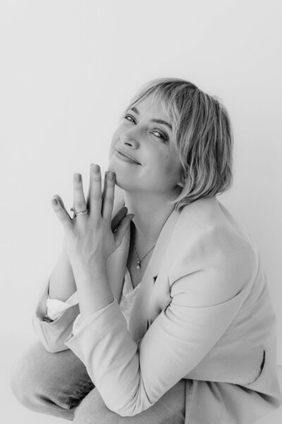 Rosanne Sarah, zelfstandig redacteur en schrijfcoach voor schrijvers van romans, zittend op de grond en kijkend in de camera.