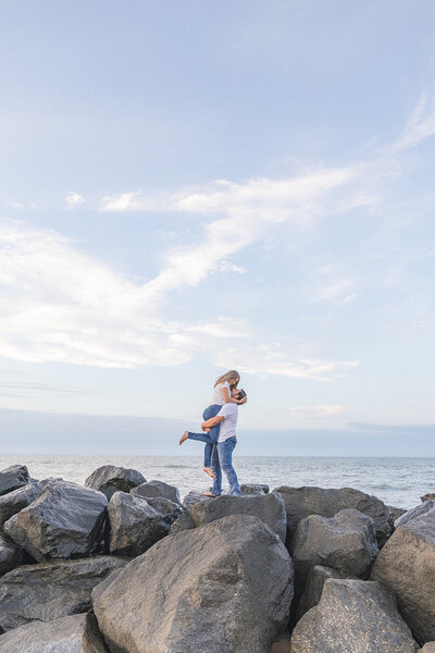 couple holds each other by the water outside the Cape Henry lighthouse