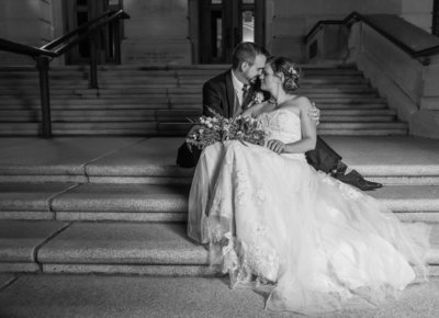 black and white wedding photo of couple sitting on stairs