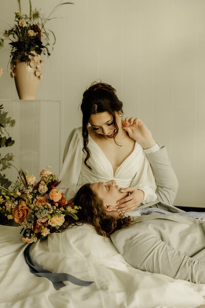 Bride and groom tenderly snuggle together surrounded by colorful florals.