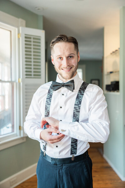 A groom adjusting cufflinks on his shirt
