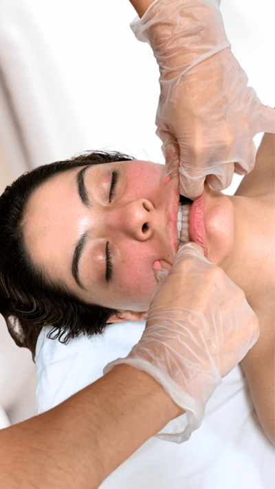Hands giving a buccal massage by massaging inside of the woman's mouth