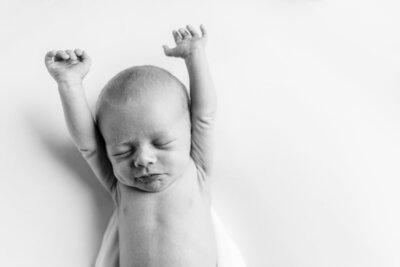 Newborn baby stretching with arms up