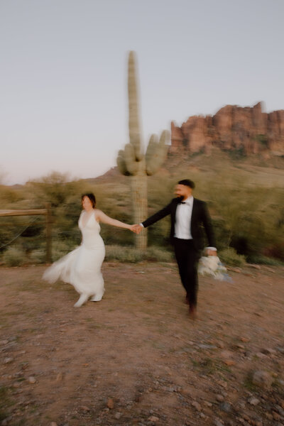 bride and groom running holding hands during outdoor desert elopement in missouri