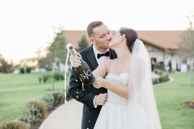 A bride and groom popping a bottle of champagne in Florida
