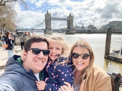 Top PPC marketer traveling the world with family, enjoying a scenic view in front of a lake with a tent and campfire, showcasing a blend of work-life balance.